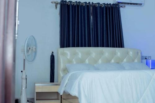 1 dormitorio con cama blanca y cortina negra en Feyintola Shortlet Apartment, en Ondo