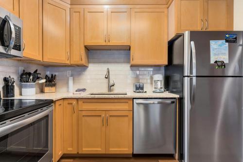 a kitchen with wooden cabinets and a stainless steel refrigerator at Bugle Pointe B20 by Estes Park Condos in Estes Park