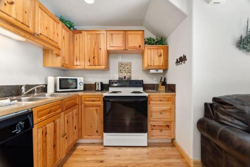 - une cuisine avec des placards en bois et une cuisinière noire et blanche dans l'établissement Creekside Condos D by Estes Park Condos, à Estes Park