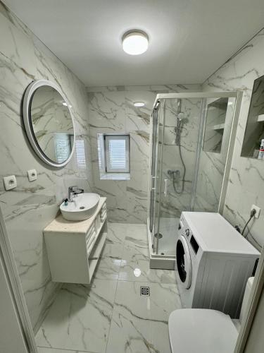 a white bathroom with a shower and a sink at Villa Rozika in Baška Voda