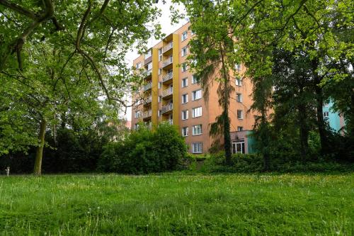 a tall building in the middle of a grass field at Moderní byt s přímým vstupem do parku v centru Ostravy in Jáma Jindřich