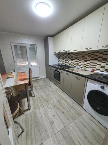 uma cozinha com armários brancos, uma mesa e um lavatório em Apartament Tecuci lux em Tecuci