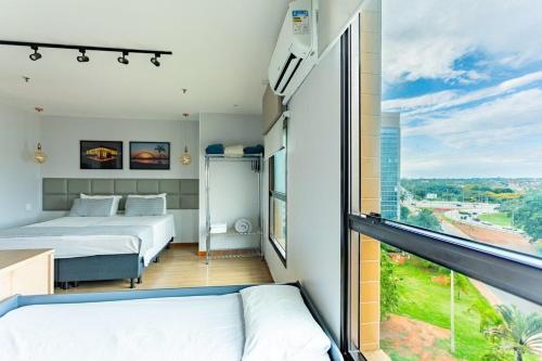 a bedroom with two beds and a large window at Apartamento no Comfot hotel in Brasilia