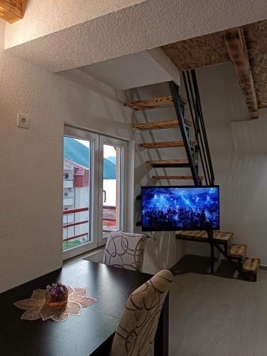 a dining room with a table and a large screen tv at Apartmani Lena in Pluzine