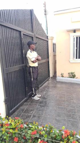 IBADAN LUXURY APARTMENT في Moniya: رجل واقف امام سياج