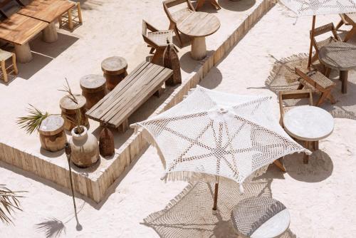 ホルボックス島にあるAWA Holbox Hotel Boutique - Beach Frontの傘、テーブル、椅子が備わる