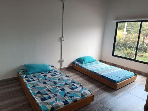 Dos camas sentadas en una habitación con ventana. en cabaña la esmeralda, en El Peñol
