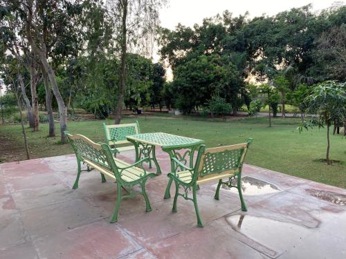 a table and two chairs sitting next to a park at Orchard At Sarai - Private cottage, Large lawn, & Pet friendly in Gurgaon