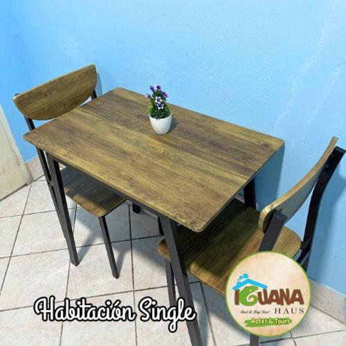 a wooden table with a vase of flowers on it at IGUANA HAUS IQUITOS in Iquitos