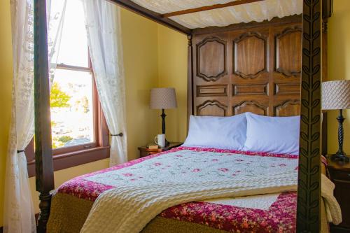 a bedroom with a bed with a wooden headboard and a window at The Pearl Inn Bed and Breakfast in Ilwaco