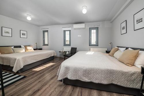 two beds in a room with white walls and wooden floors at BLAHA ROOMS in Balatonfüred