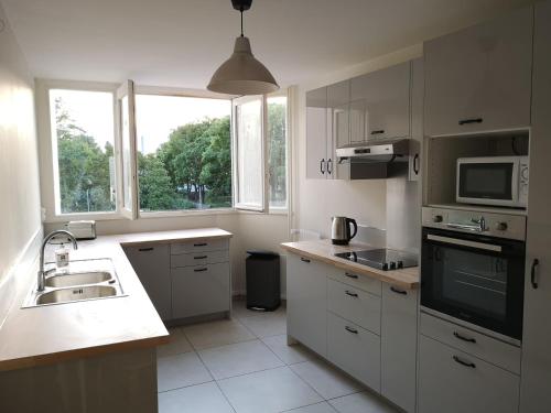 a white kitchen with a sink and a microwave at Chambre proche Stade de France in Saint-Denis