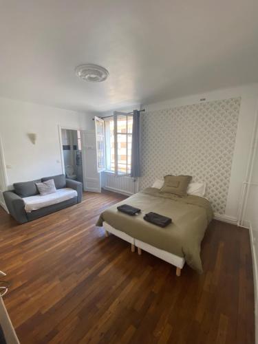 een slaapkamer met een bed en een bank bij Studio Montrouge proche Centre in Montrouge