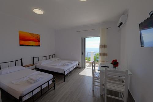 Cette chambre comprend 2 lits, une table et une fenêtre. dans l'établissement Eduard Lagji Apartament, à Lukovë