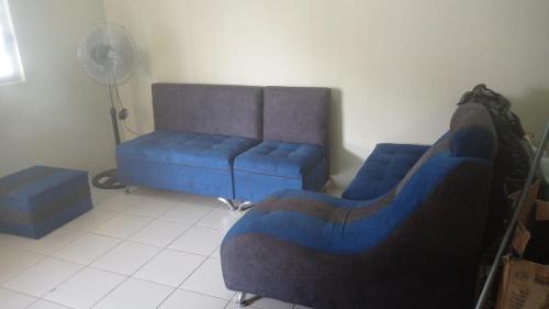 a living room with a blue couch and a fan at CASA VACACIONAL URBANIZACIÓN PROGRESIVA in Manta