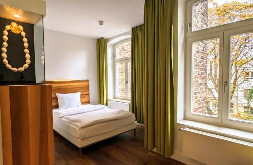 a bedroom with a bed and a large window at HOPPER Hotel St. Josef in Cologne