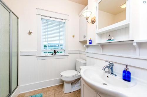 Baño blanco con aseo y lavamanos en Crawling Distance Beach House, en Pensacola