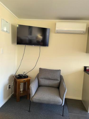 a room with a chair and a tv on the wall at Aquarius Motel in Ohope Beach