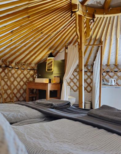 two beds in a room with a wooden ceiling at Náttúra Yurtel in Haukadalur