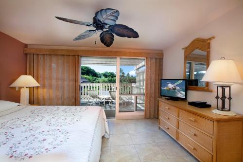 a bedroom with a bed and a television and a balcony at Ocean views & turtle watching - Ks b3 Sullivan in Kahana