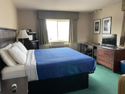 a hotel room with a bed and a desk at Heritage Inn Hotel in Watertown