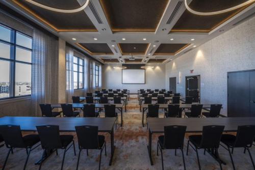 a conference room with tables and chairs and a screen at Hotel Indigo Tulsa DWTN/Entertainment Area in Tulsa