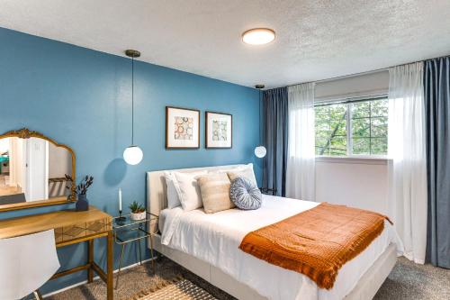 a bedroom with blue walls and a bed and a desk at Vibrant Tacoma Retreat, Near Point Defiance Park! in Tacoma
