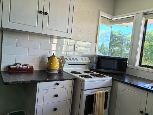 a kitchen with a white stove and a microwave at Aquarius Motel in Ohope Beach
