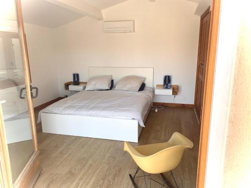 - une chambre avec un lit et une chaise jaune dans l'établissement Villa d’architecte avec piscine entre vignes et forêt, à Saint-Cyr-sur-Mer