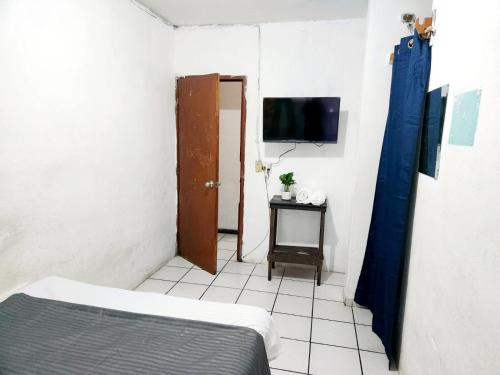 a small room with a bed and a tv at Hotel El Mexicano Tepic Centro in Tepic