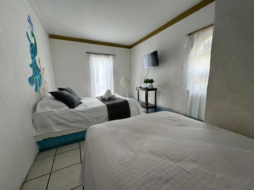 a bedroom with two beds and a window at Hotel El Mexicano Tepic Centro in Tepic