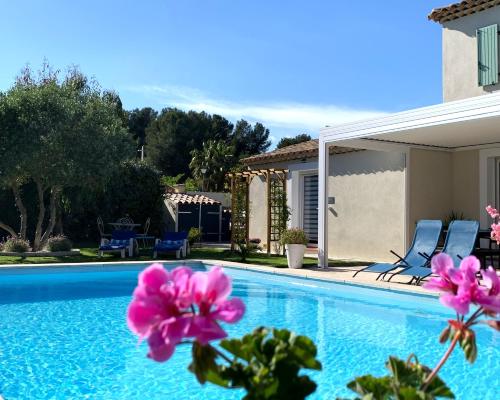 a swimming pool with pink flowers next to a house at Chambre d'hôtes de charme MERBLEUESOLEIL in Six-Fours-les-Plages