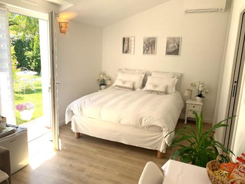 um quarto com uma cama branca e uma porta de vidro deslizante em Chambre d'hôtes de charme MERBLEUESOLEIL em Six-Fours-les-Plages