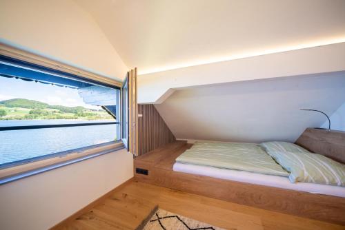 a bed in a small room with a window at Urlaub am See Seehaus Salzburg Mattsee Obertrum Seeham Salzburger Seenland in Obertrum am See