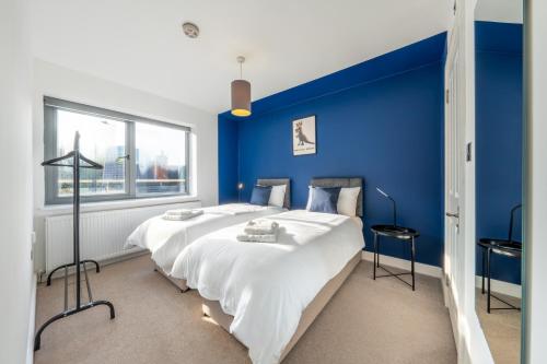 a blue bedroom with a large bed and a blue wall at Modern Apartment In Central Watford by Hampton - Ideal For Professionals & Contractors in Watford