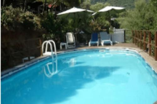 - une piscine bleue avec 2 chaises et un parasol dans l'établissement Villa vieux rose avec accès piscine, à Cargèse