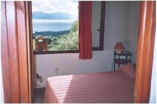 - une chambre avec un lit et une fenêtre avec un chien dans l'établissement Villa vieux rose avec accès piscine, à Cargèse