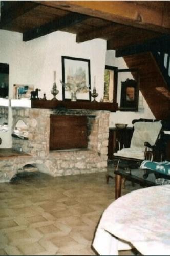 - un salon avec une cheminée en pierre et une chaise dans l'établissement Villa vieux rose avec accès piscine, à Cargèse