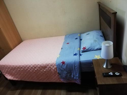 a bed with a pink bedspread with stars on it at hostal NAUU in Concepción