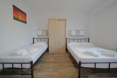 two twin beds in a room with white walls at Eduard Lagji Apartament in Lukovë