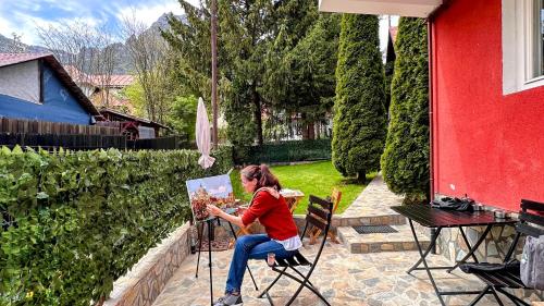 a woman sitting in a chair painting a picture at Valea Albă View - SELF CHECK-IN in Buşteni