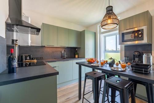 une cuisine avec des placards verts et un îlot avec des tabourets de bar dans l'établissement Envole - moi, à Mont-Saint-Aignan