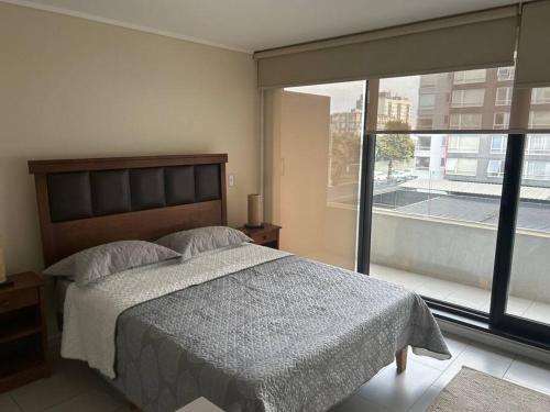 a bedroom with a bed and a large window at Departamento Estudio, entero in Temuco