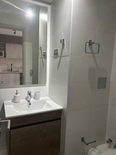 a bathroom with a sink and a shower with a mirror at Departamento Estudio, entero in Temuco