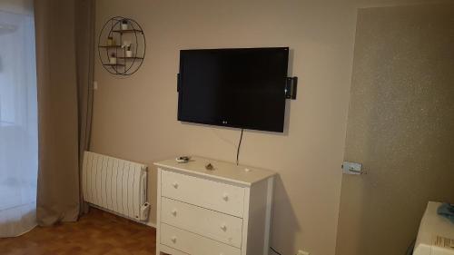 - une télévision à écran plat sur un mur au-dessus d'une commode dans l'établissement Studio place saint clair, au Cap d'Agde