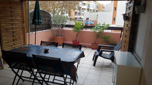 une table et des chaises sur un balcon avec des plantes en pot dans l'établissement Studio place saint clair, au Cap d'Agde