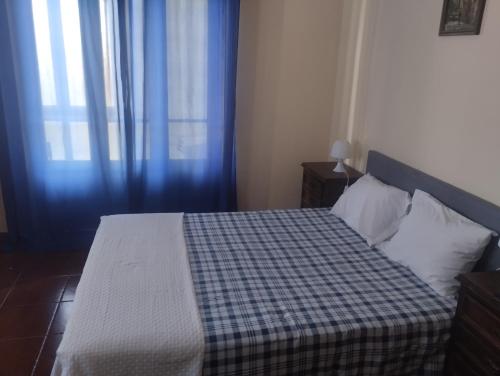een slaapkamer met een bed met een geruite deken bij Alojamento Local, Cantinho Verde in Corroios