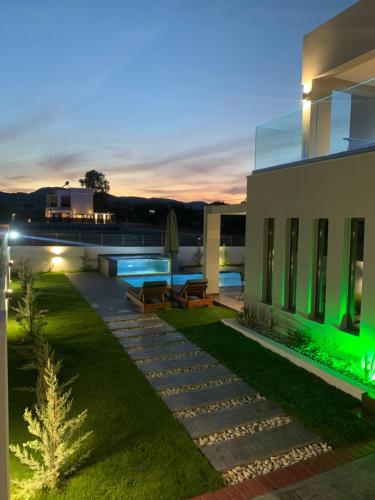 un patio trasero de una casa con piscina por la noche en Mamica Luxury Villa en Laganas