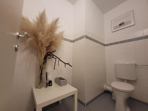 a white bathroom with a toilet and a table at Jana Vienna Airport Apartment in Schwechat