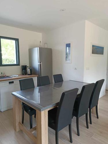 une table à manger avec des chaises noires et une cuisine dans l'établissement Maison neuve 3 chambres confortable au calme Nivillac Morbihan, à Nivillac